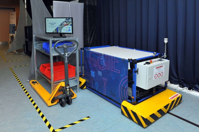 Logisztika A szcenárió bemutatja, hogy miként lehet egy automatikusan, logisztikai környezetben működő lokalizációs rendszer segítségével a logisztikai objektumokat, eszközöket, nyersanyagot stb. nagy pontossággal követni, és az így nyert információt hogyan lehet felhasználni a folyamatok veszteségeinek csökkentésére, hatékonyságuk javítására. A demonstráció bemutatja azokat az alapkomponenseket (pl. AGV, kézi hidraulikus emelő) és ezen helymeghatározók kapcsolatát, melyek a gyáron belüli anyagellátási területek kulcsfontosságú elemei. Együttműködő partner: BME Anyagmozgatási és Logisztikai Rendszerek Tanszék